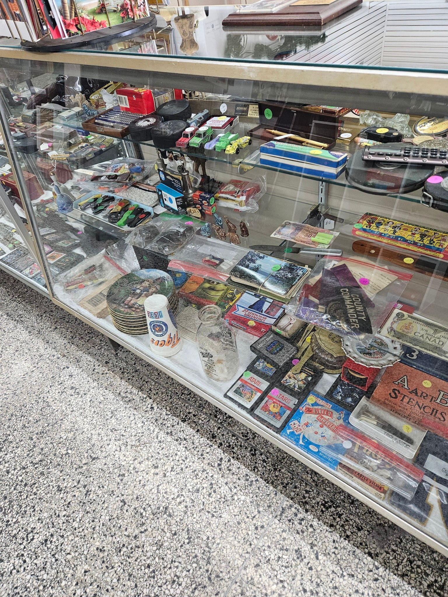 Glass display case filled with assorted toys, candy, and small packaged items in a store.