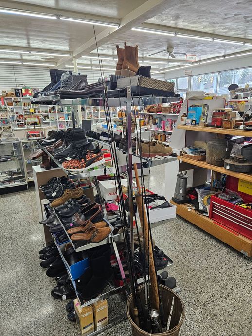 A retail store aisle with fishing rods, gear racks, and shelves of assorted sporting goods