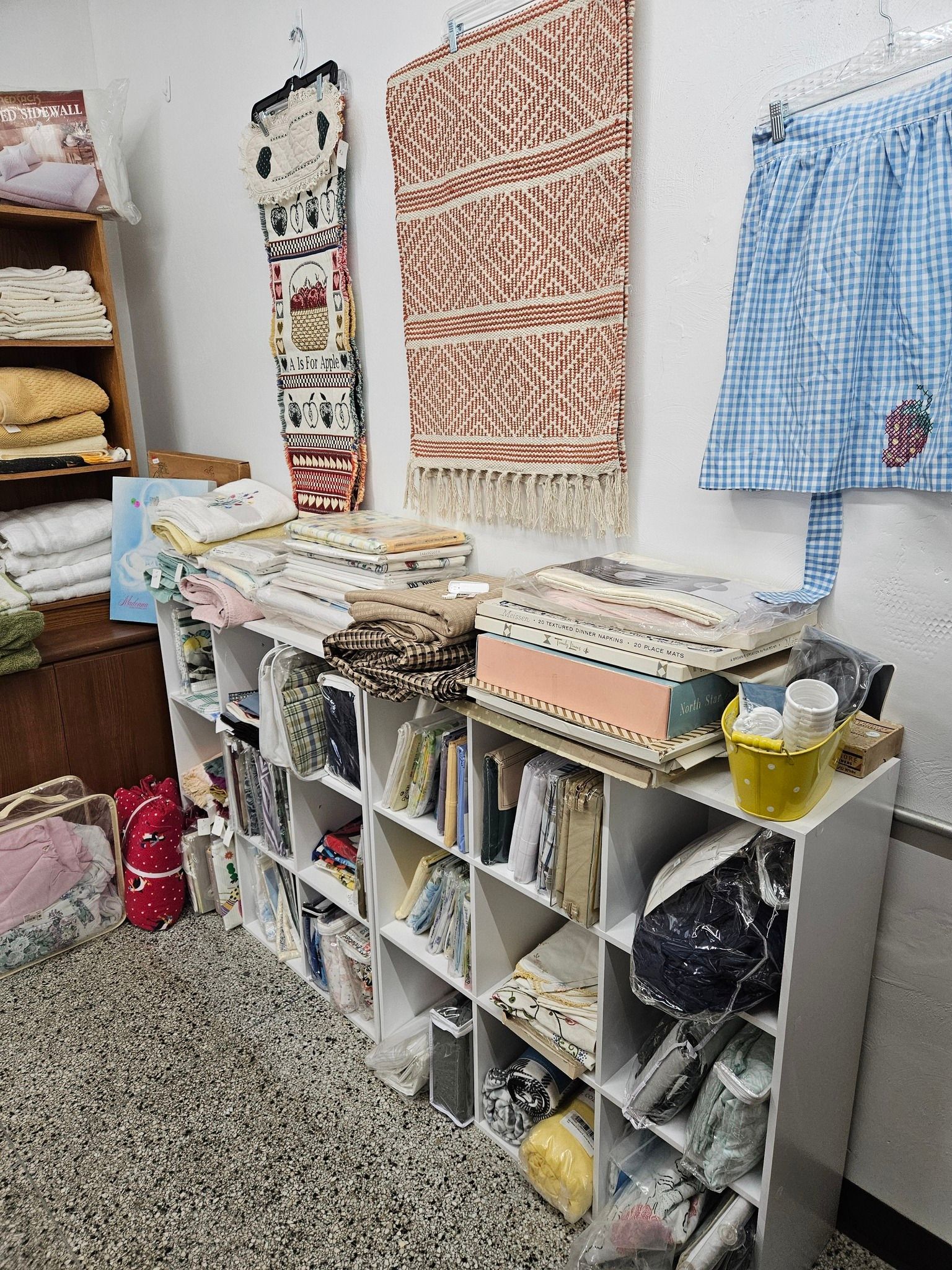 Fabric workshop shelves with folded textiles, patterned wall samples, and a gray storage cubby unit