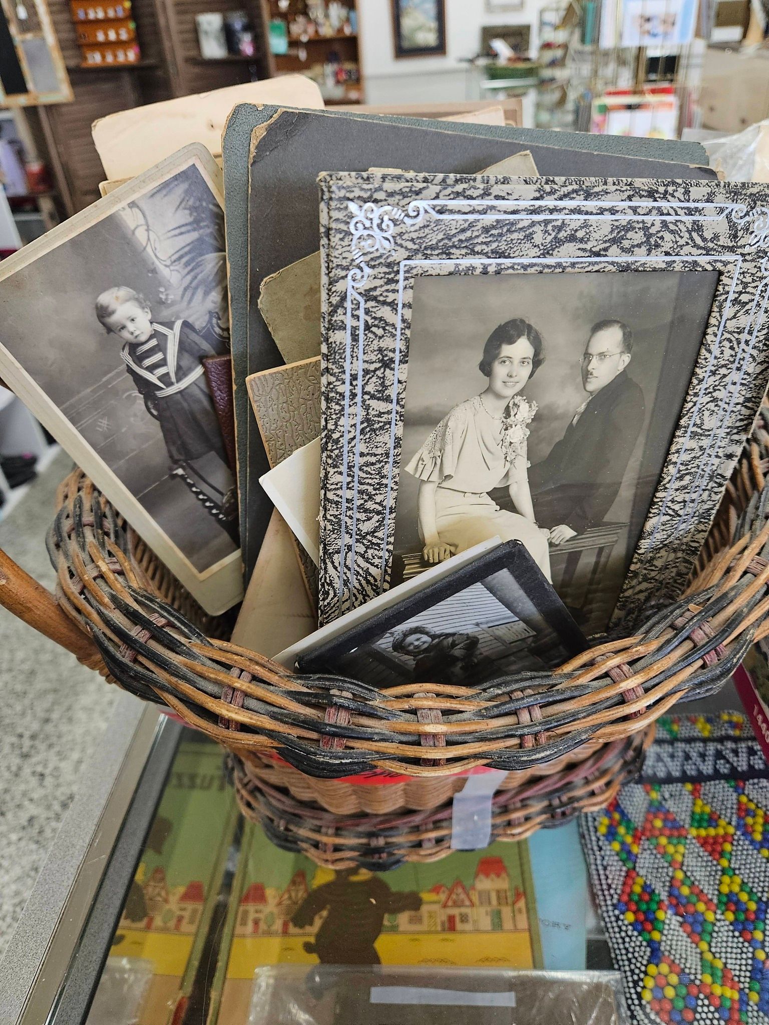 Basket of vintage black-and-white portrait prints and framed photos on a store table