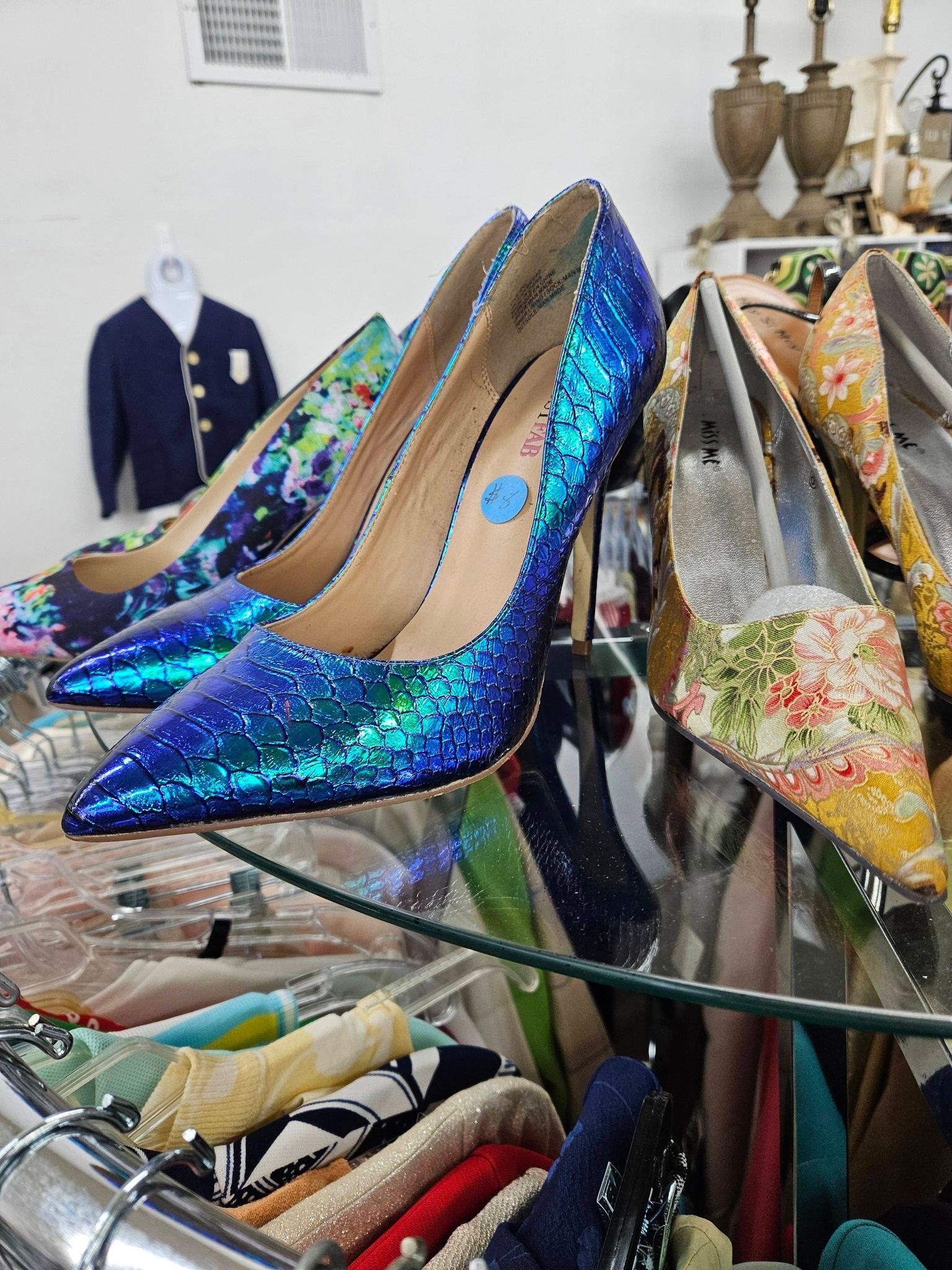 Sparkly blue high heels on a glass display table in a boutique.