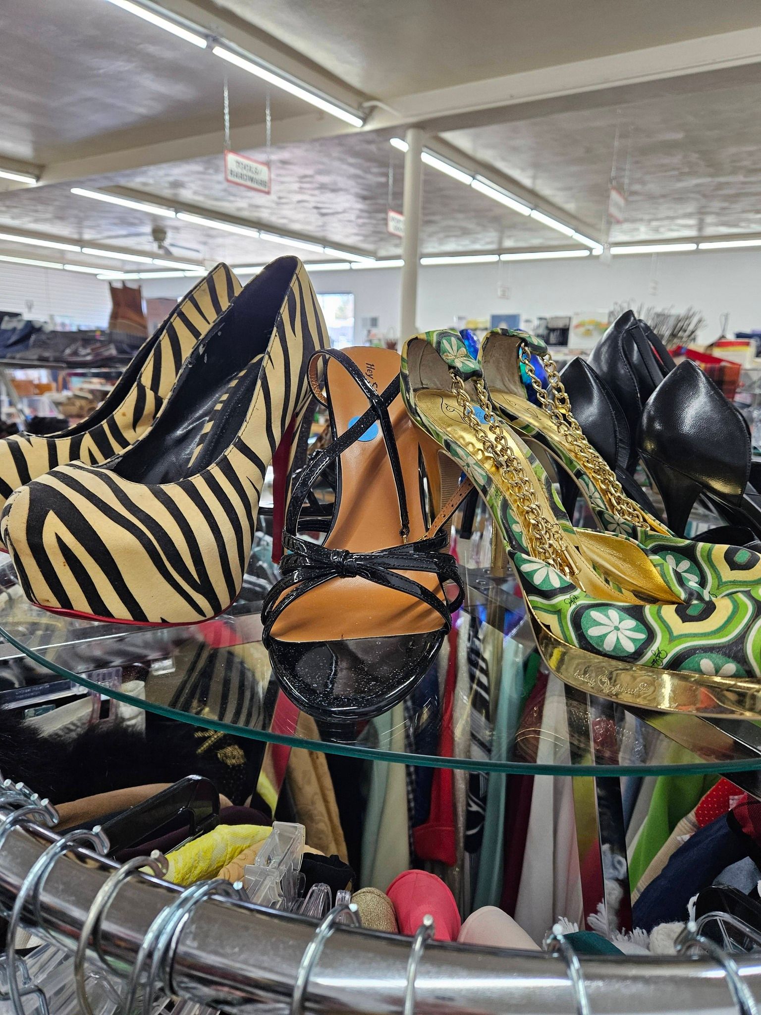 Assorted colorful high-heeled shoes displayed on a store rack under bright indoor lighting