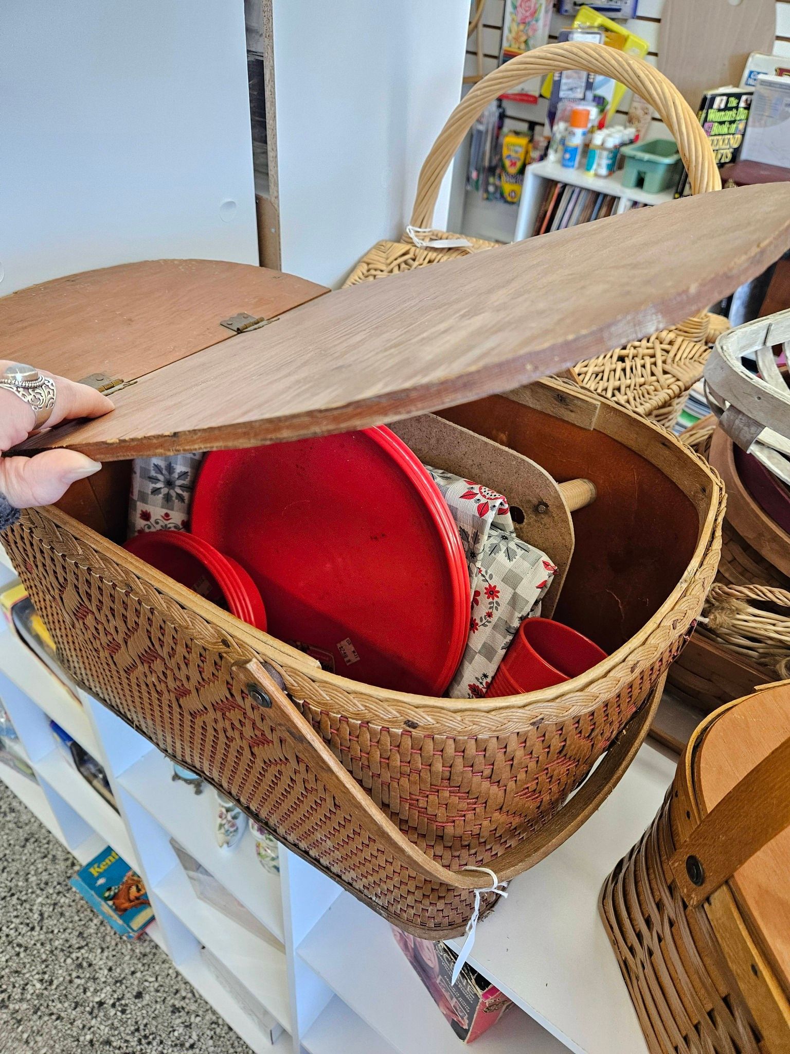 Hand opening a woven basket with a red lining on a table
