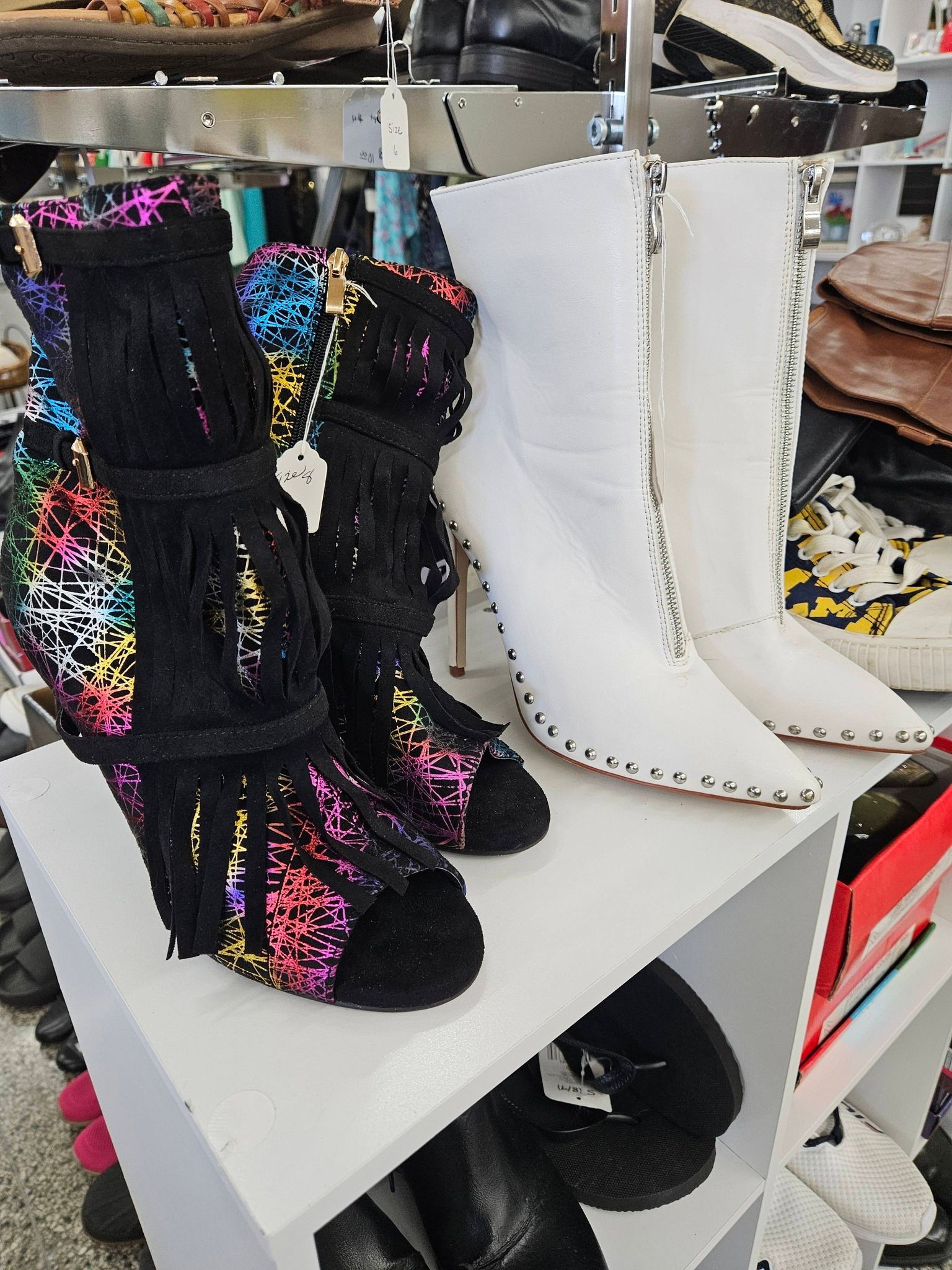 Black beaded boots and white knee-high boots displayed on a store shelf