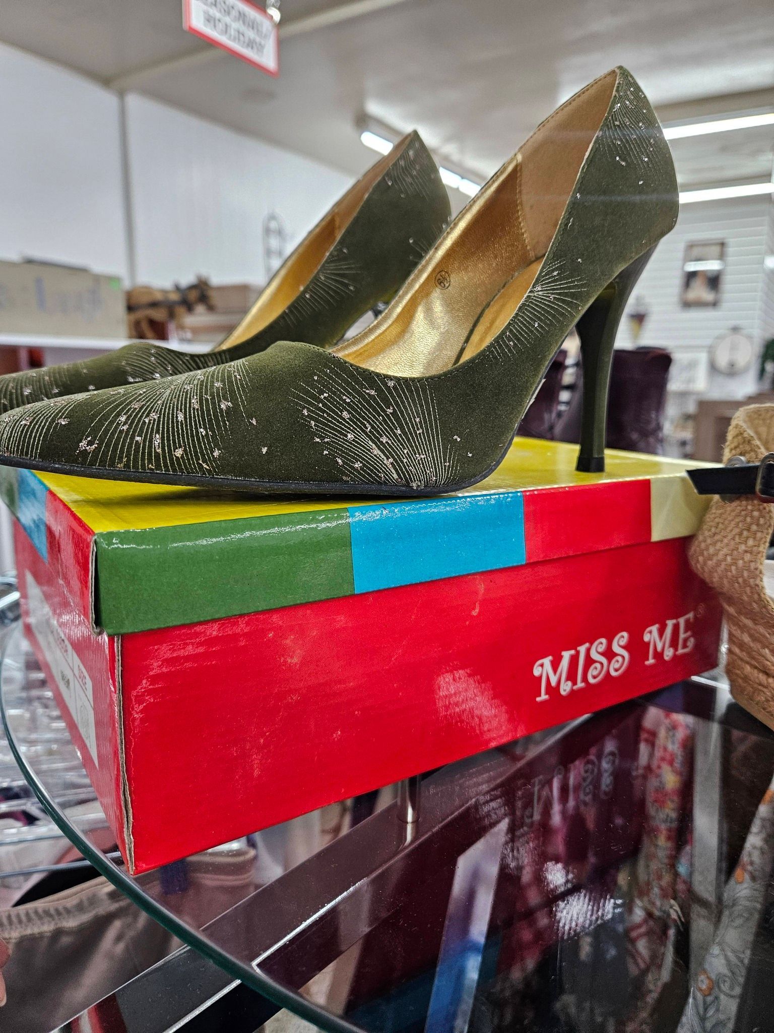 Sparkly gold high heels on a colorful shoe box in a store setting