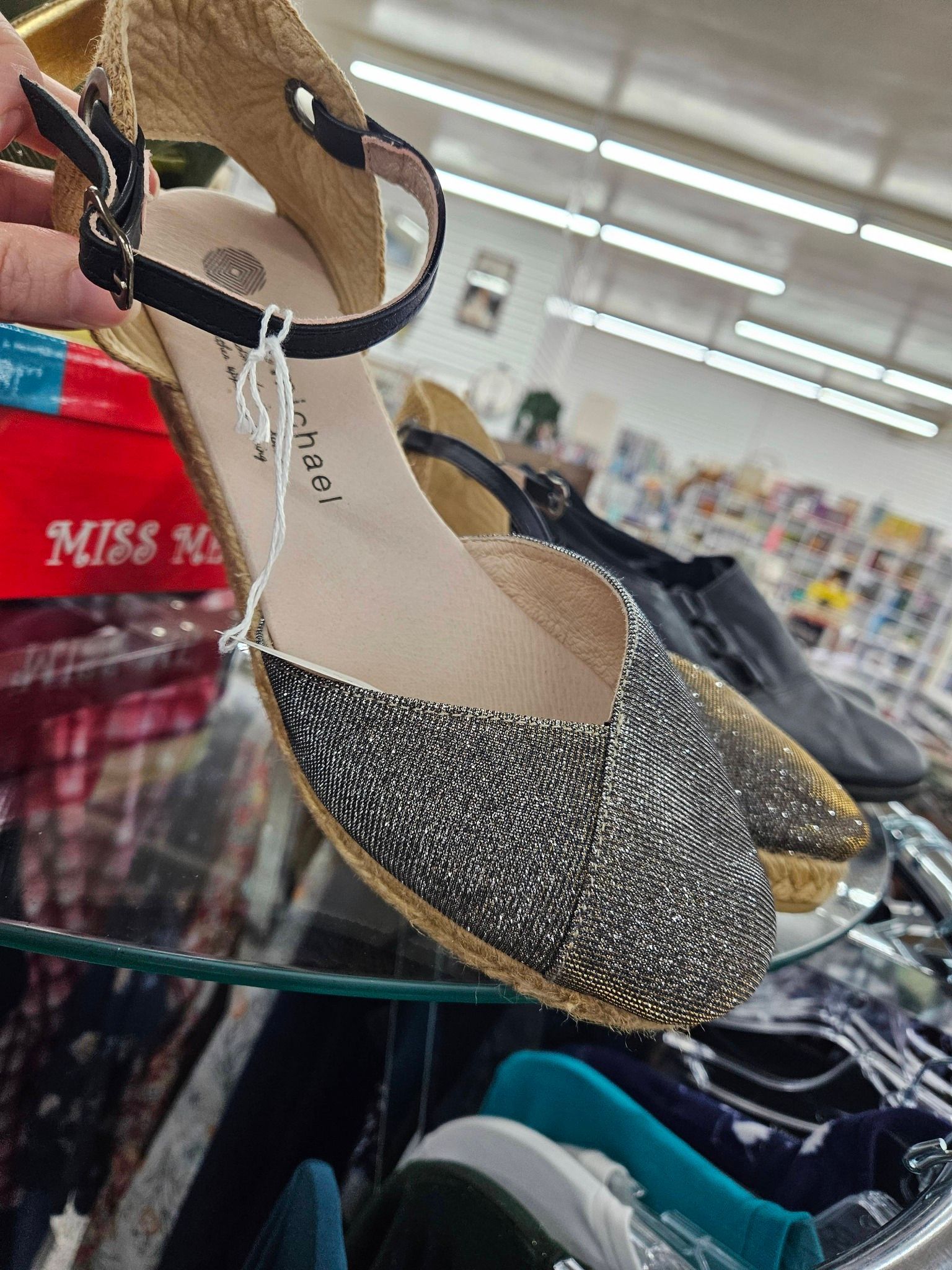 Sparkly silver slingback shoes on a store display shelf indoors