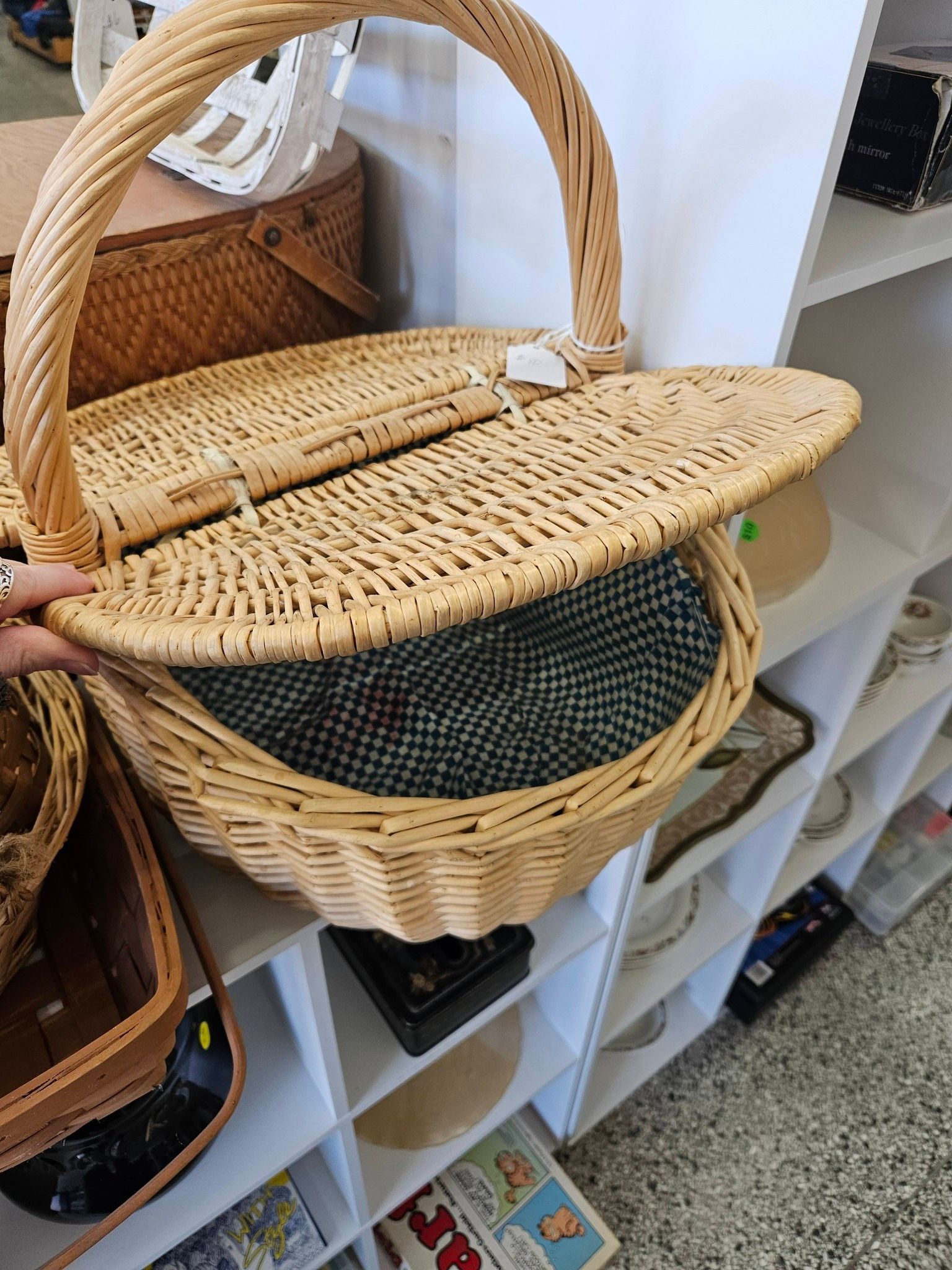 Wicker basket with woven lid on a white shelf in a store display