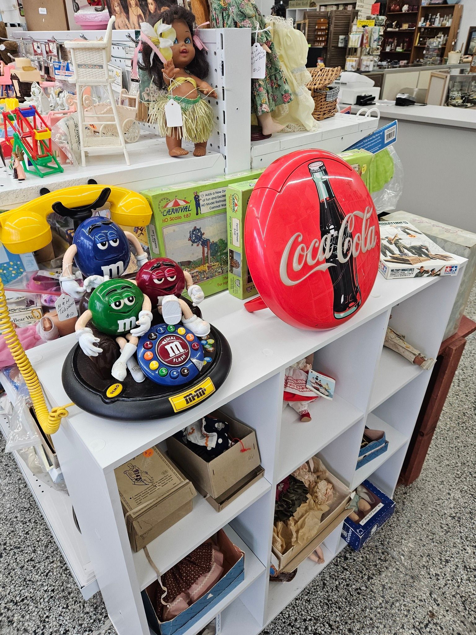 White display shelf with colorful Coca-Cola and souvenir balls in a store aisle