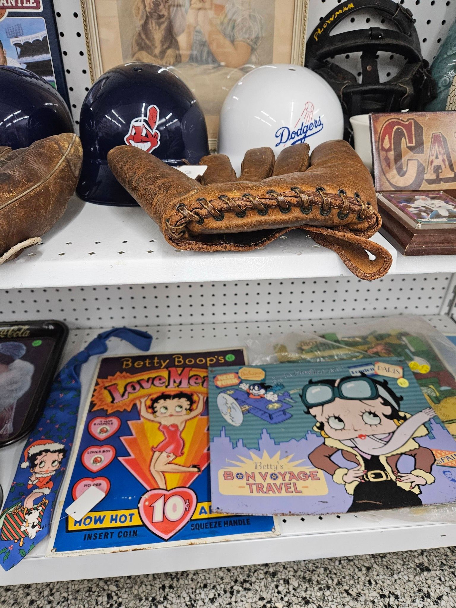 Assorted novelty helmets and colorful comic-style signs on a store shelf, including a woven baseball glove display