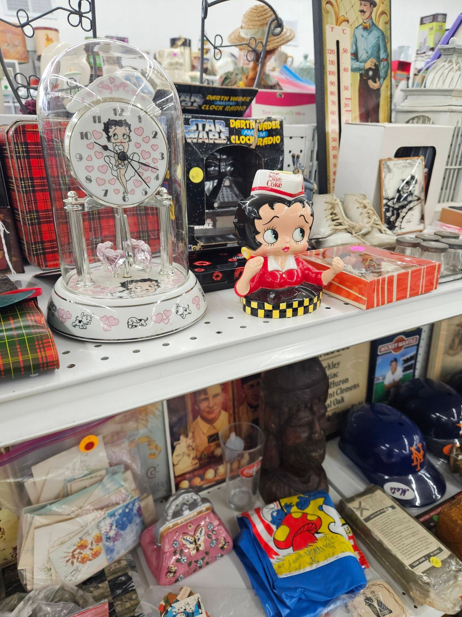 Store shelf with decorative items, including a snow globe, Betty Boop figurine, and colorful packaged goods.
