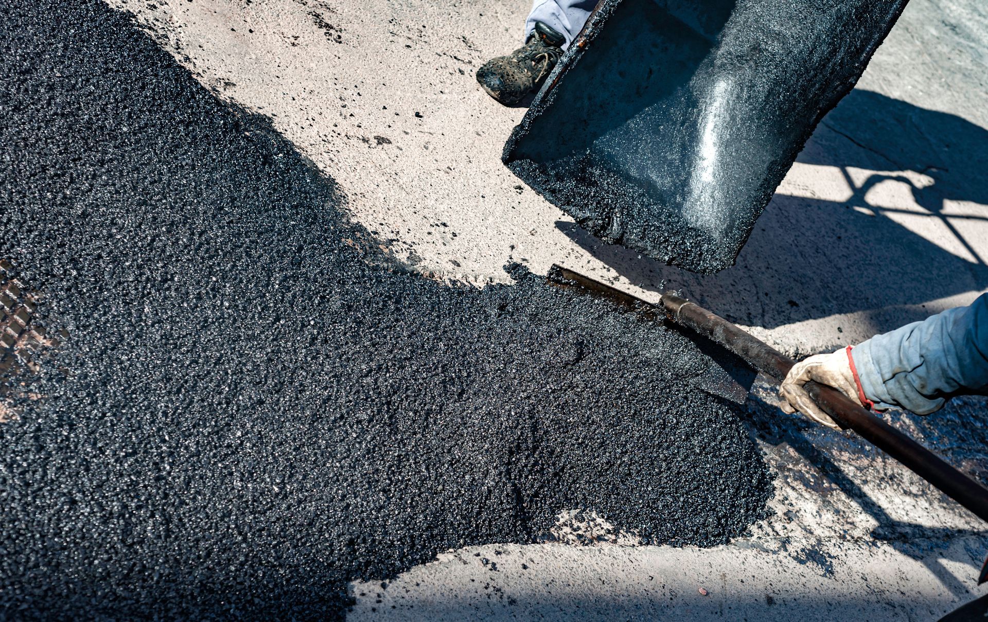 Workers spreading black asphalt with shovels on a road surface Workers spreading black asphalt with shovels on a road surface