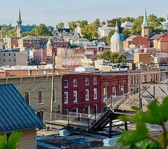 Colorful hillside cityscape with brick buildings, church steeples, and rooftops under a clear sky Colorful hillside cityscape with brick buildings, church steeples, and rooftops under a clear sky
