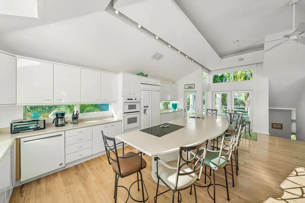 Bright white kitchen with a large island, cabinets, and bar seating.