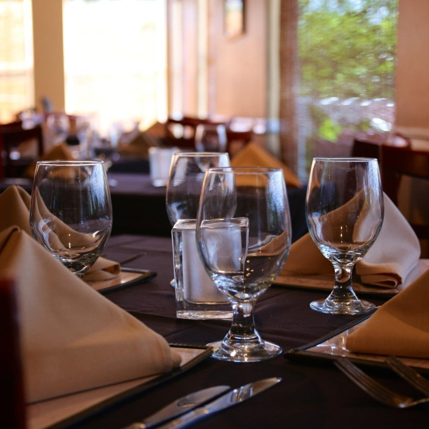 Restaurant table set with glasses, napkins, and silverware.