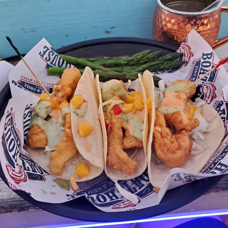 Fish tacos with mango salsa and asparagus, served in a restaurant setting.