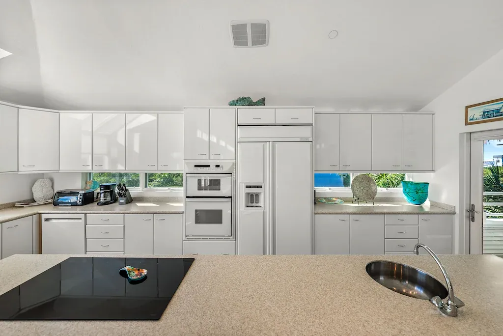 Bright, modern kitchen with white cabinets, stainless steel appliances, and a large central island.