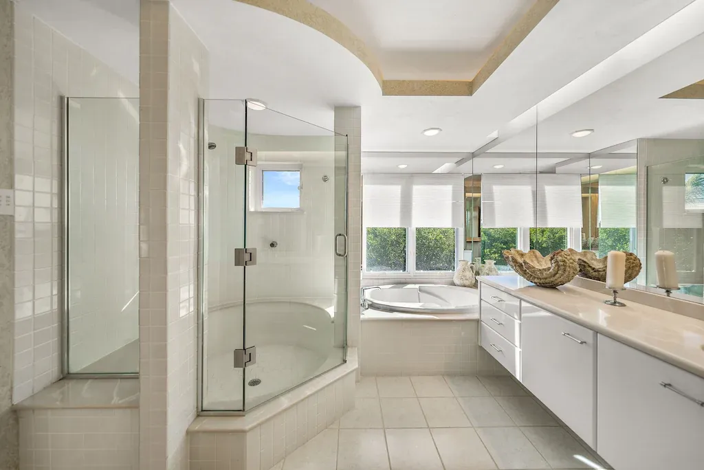 Luxurious white bathroom with glass shower, white cabinets, and tub.