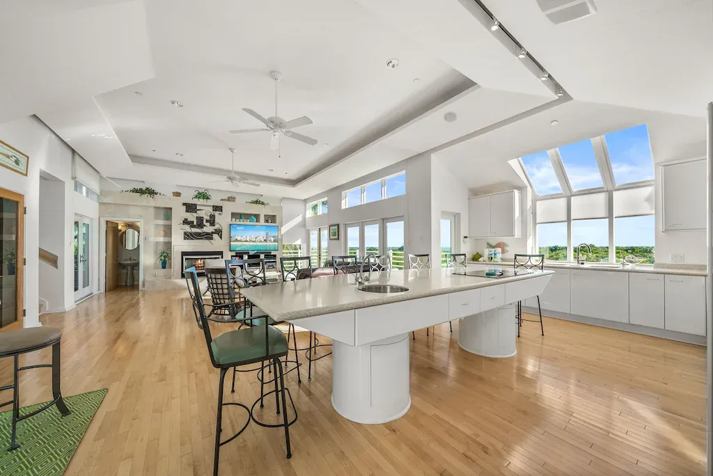Spacious, bright kitchen with large island, high ceilings, and a wall of windows overlooking a view.