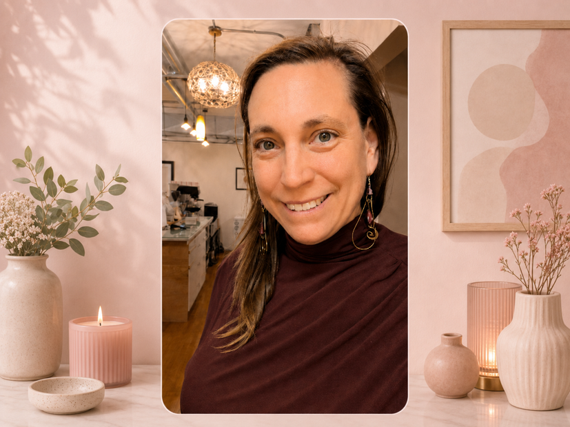 Smiling woman in a burgundy top in a warm, softly lit room with candles and vases