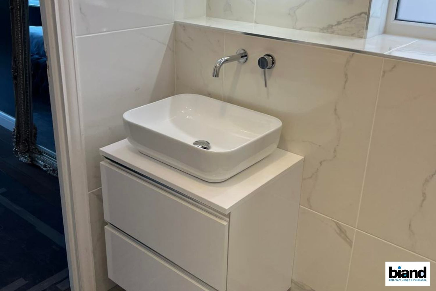 White modern bathroom vanity with sink, drawers, and wall-mounted faucet.