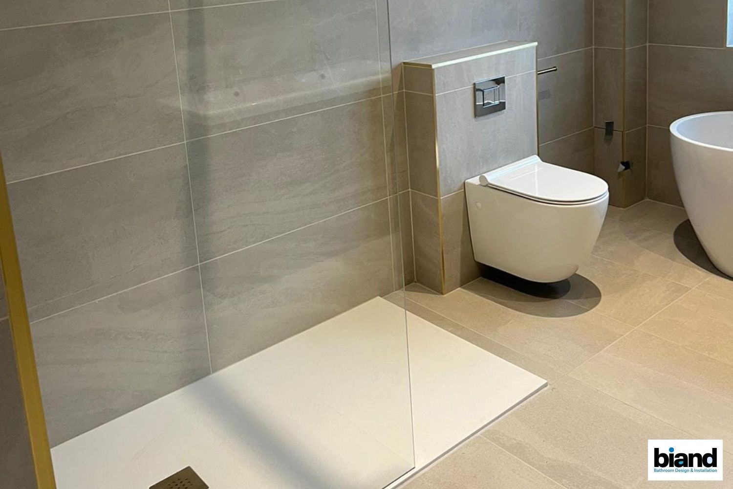 Modern bathroom with a wall-mounted toilet, a white shower base, and light-colored tiles.
