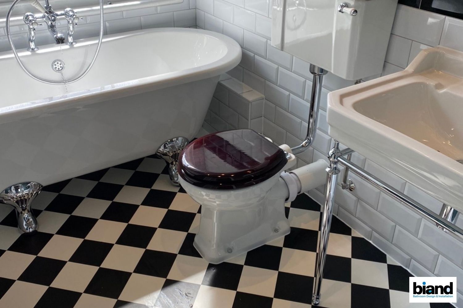 Bathroom with black and white checkered floor, white bathtub, toilet with dark seat, and white sink.