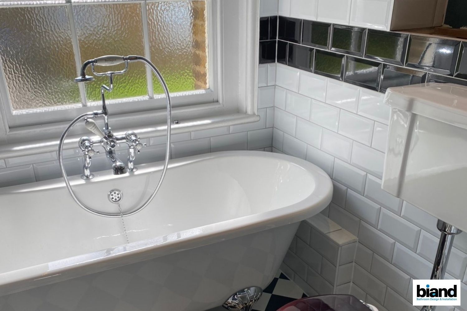 Clawfoot bathtub in a bathroom with white subway tiles, a window, and chrome fixtures.