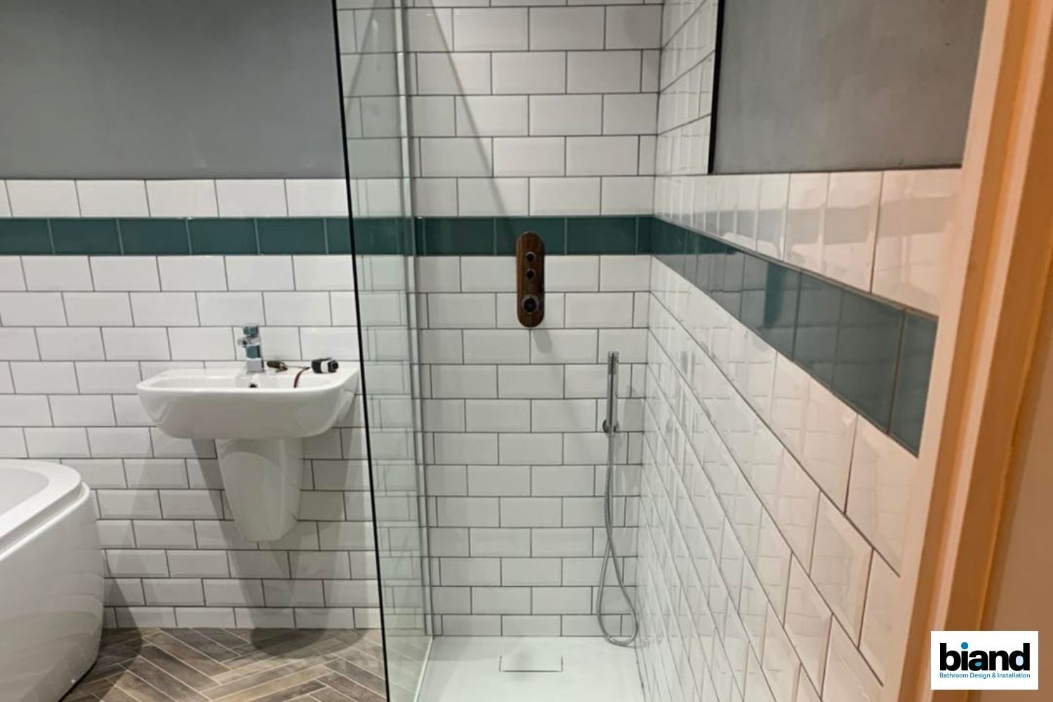 Bathroom with white subway tile, teal accent, glass shower, pedestal sink.