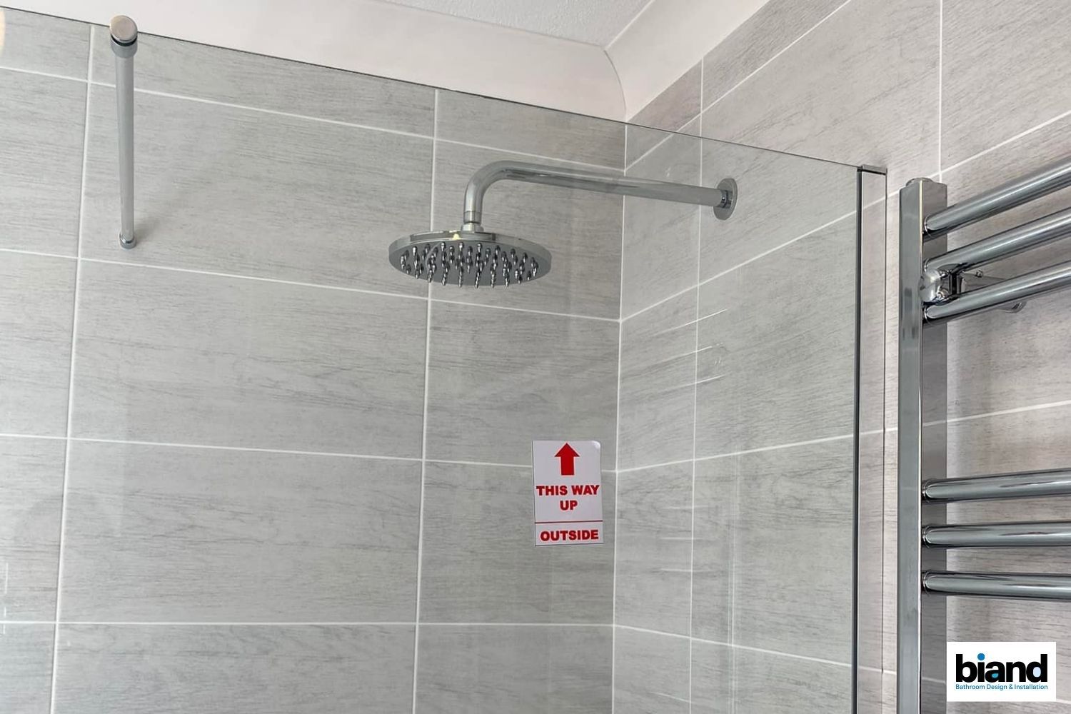Shower with glass panel, rain shower head, and grab bar. Red