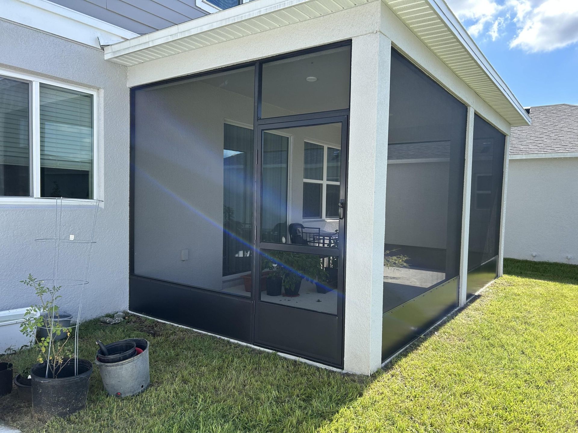 A screened in porch in the backyard of a house