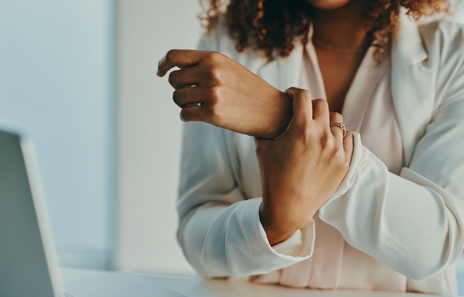 A woman at her desk holding her sore wrist.