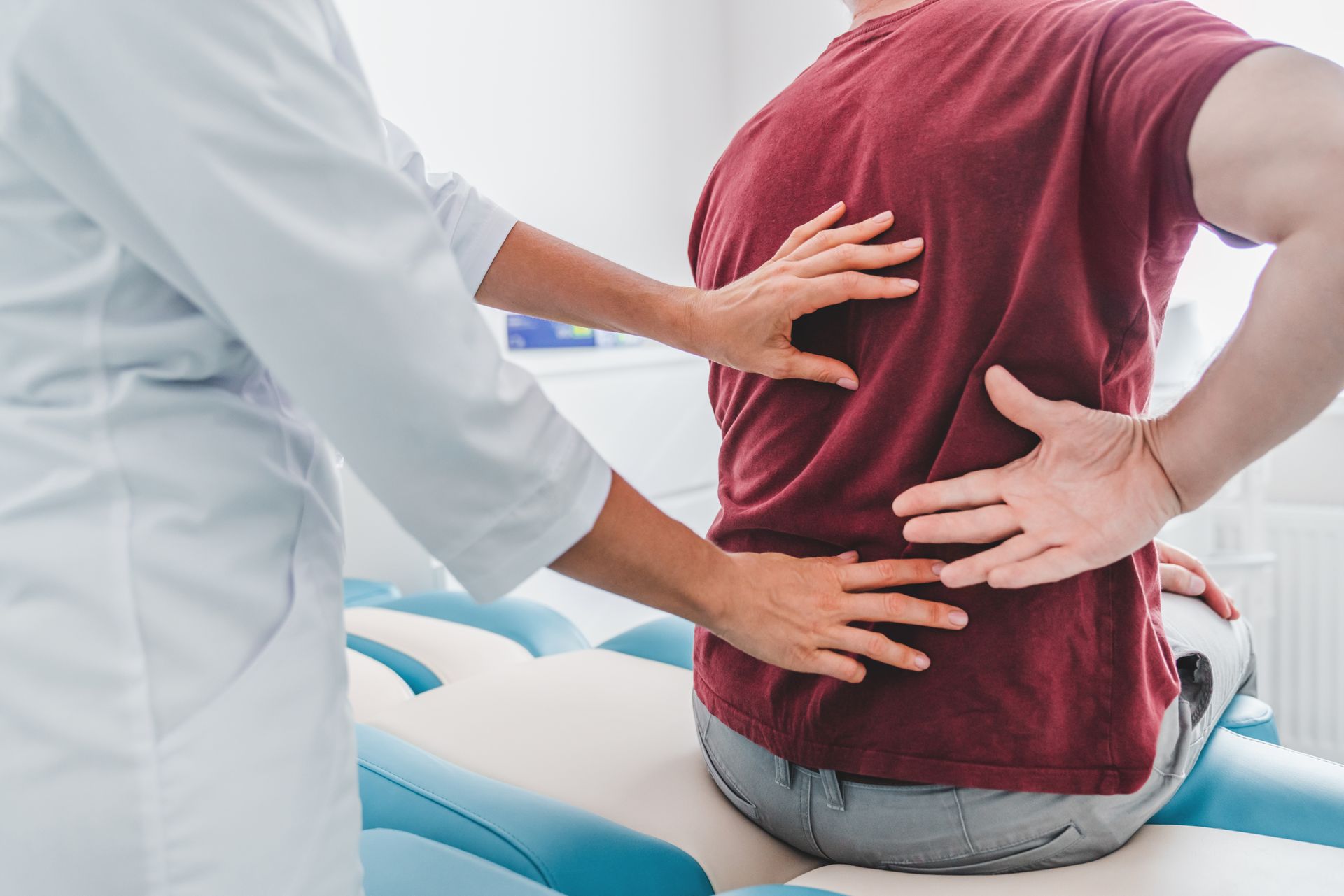 A doctor is examining a patient 's back in a hospital.