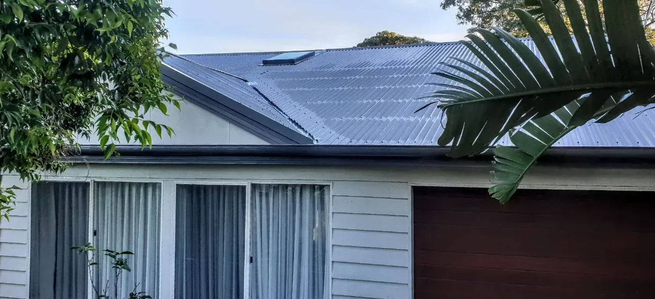 A Man is Installing a Skylight on the Roof of a Building — Coast Metal Roof & Gutter In Tumbi Umbi, NSW