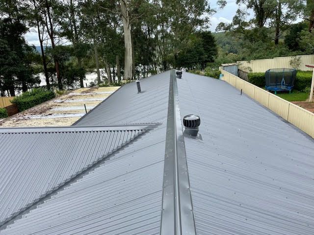 A grey roof with multiple whirlybirds on top — Coast Metal Roof & Gutter In Tumbi Umbi, NSW