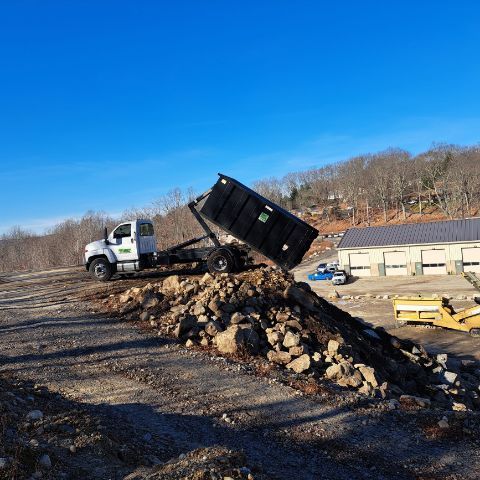 A dump truck is sitting on top of a pile of rocks dumpster rental