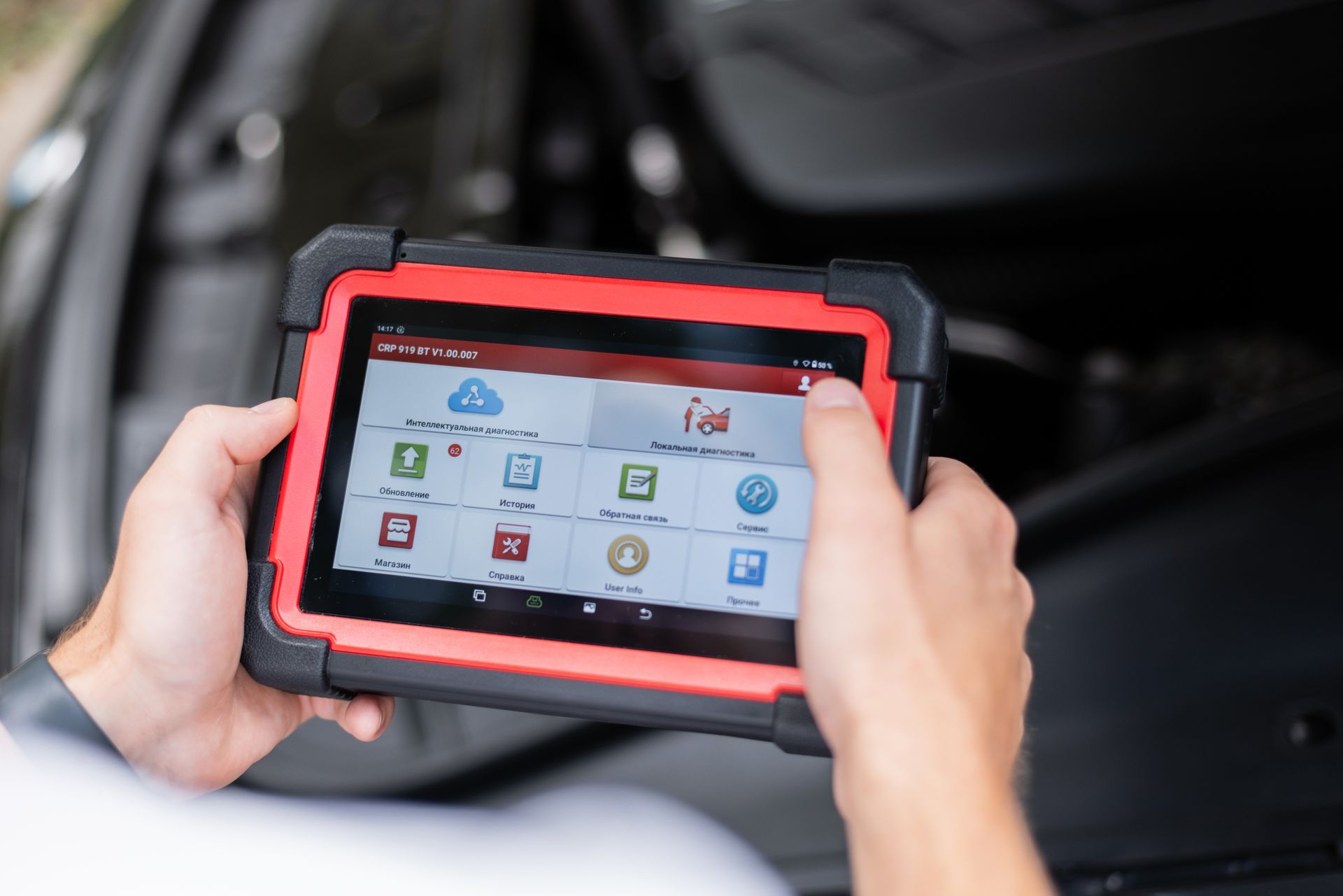 Hands holding a rugged tablet with app icons inside a car