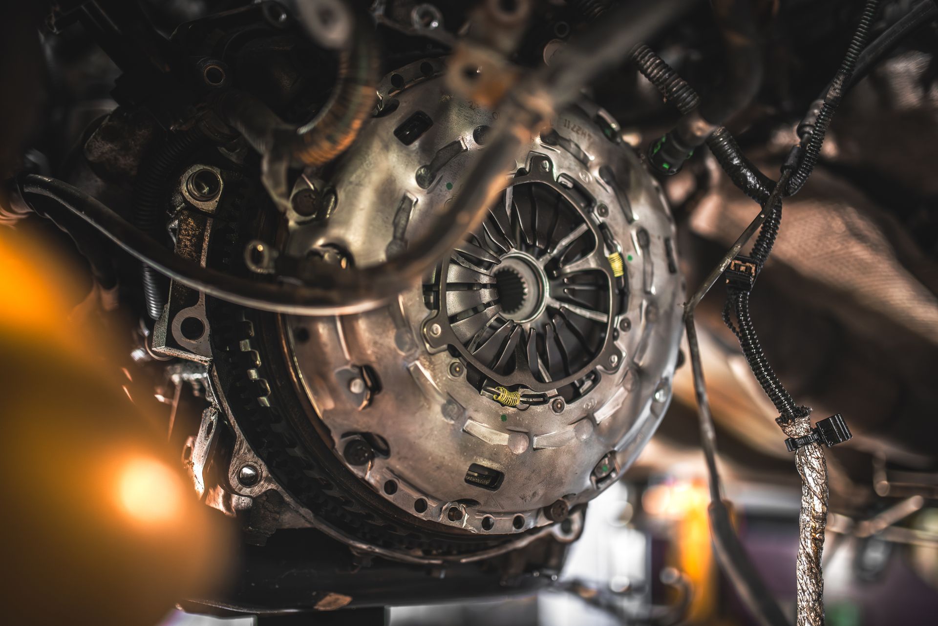Close-up of a metal engine or mechanical assembly with gears, chains, and warm workshop lighting