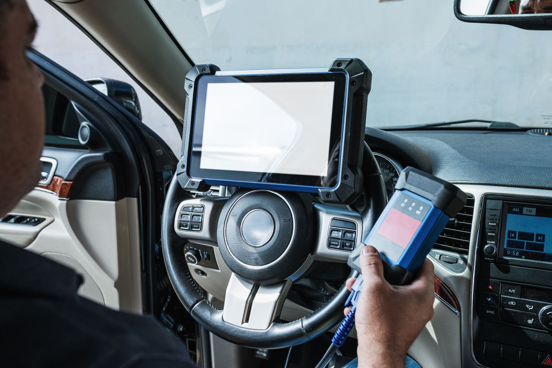 Driver using a phone beside a dashboard-mounted tablet in a car