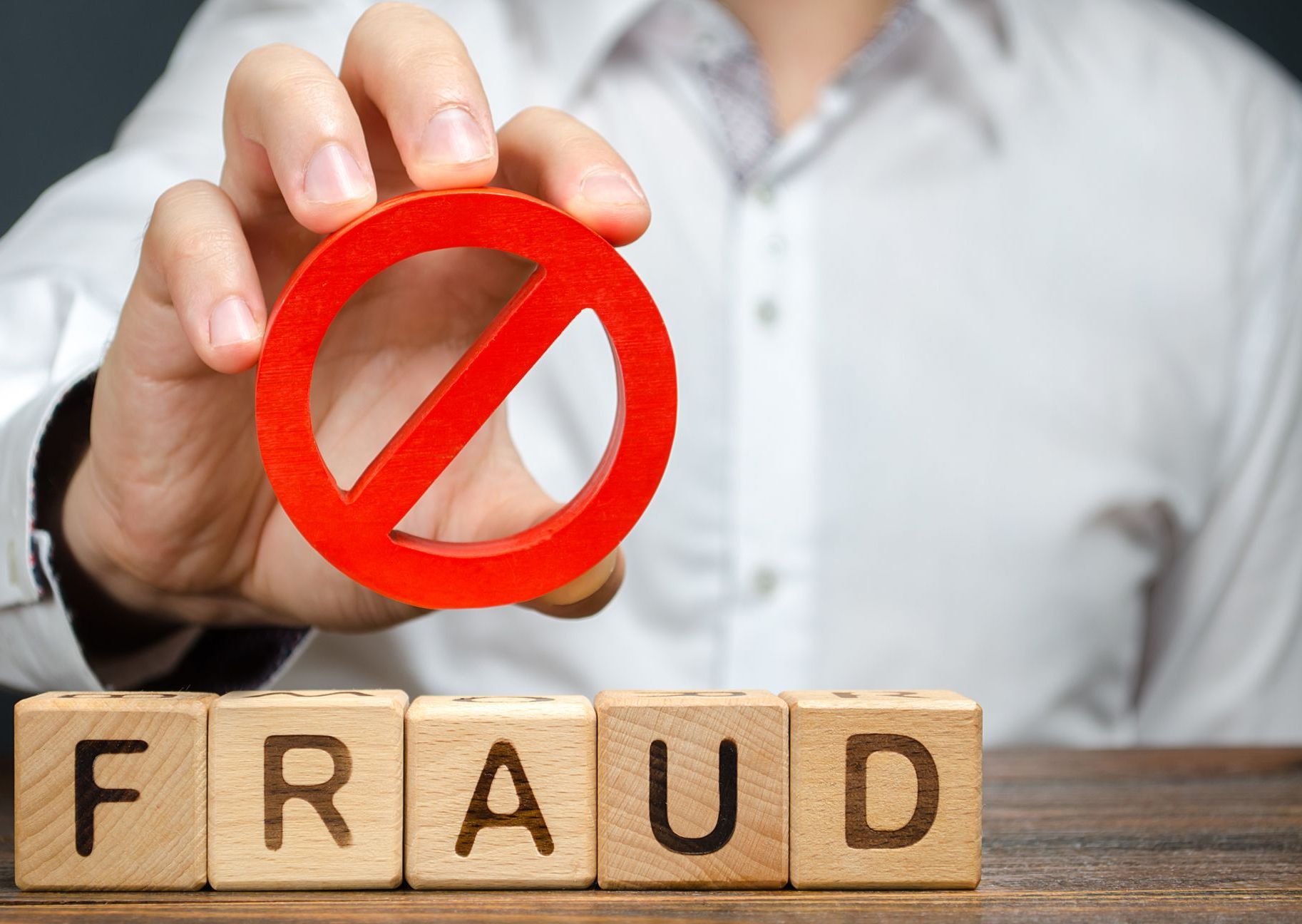 A man holds a red NO prohibition symbol over word fraud
