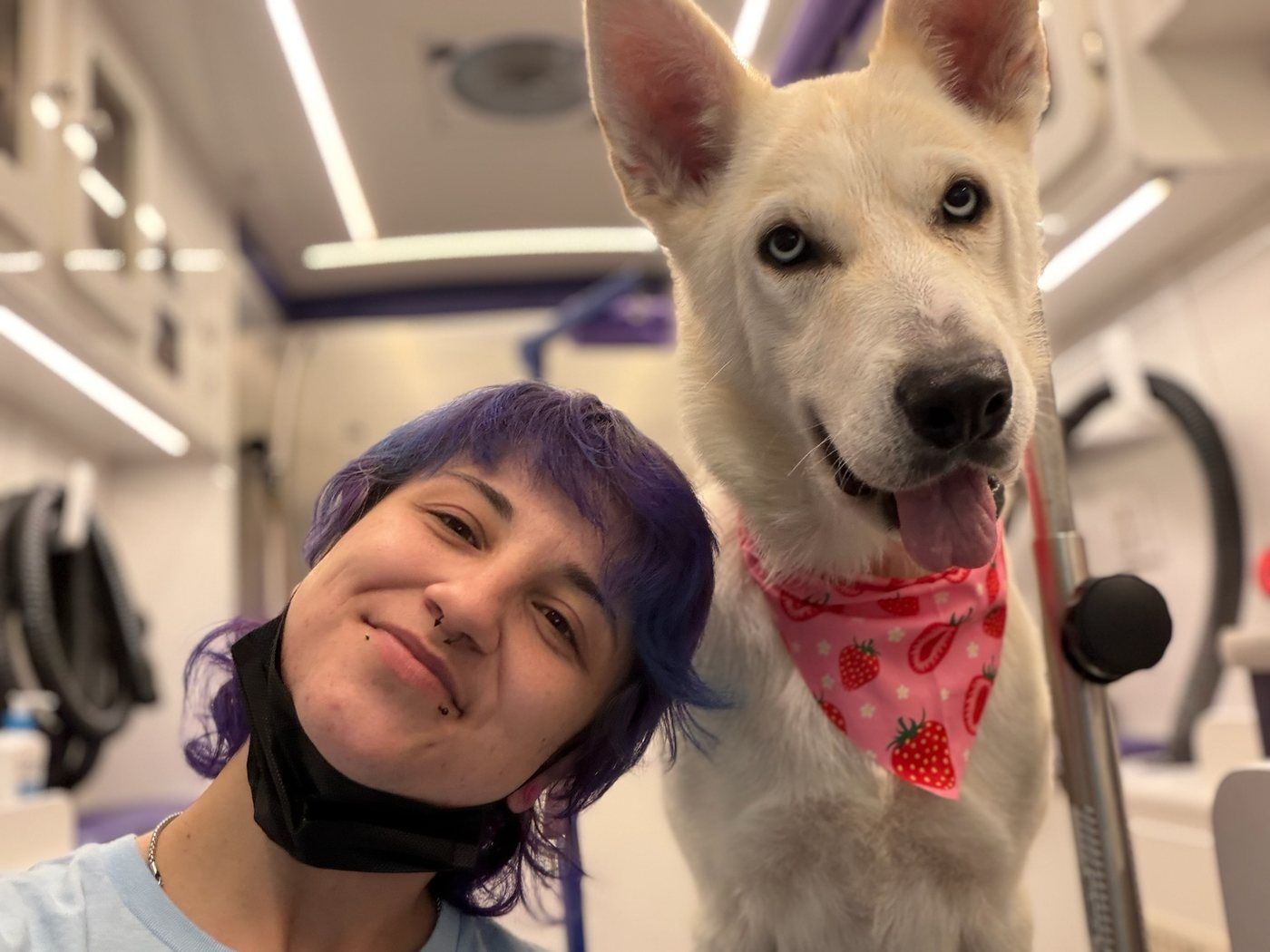 A Boops N' Bubbles groomer with a freshly groomed shelter dog wearing a bandana