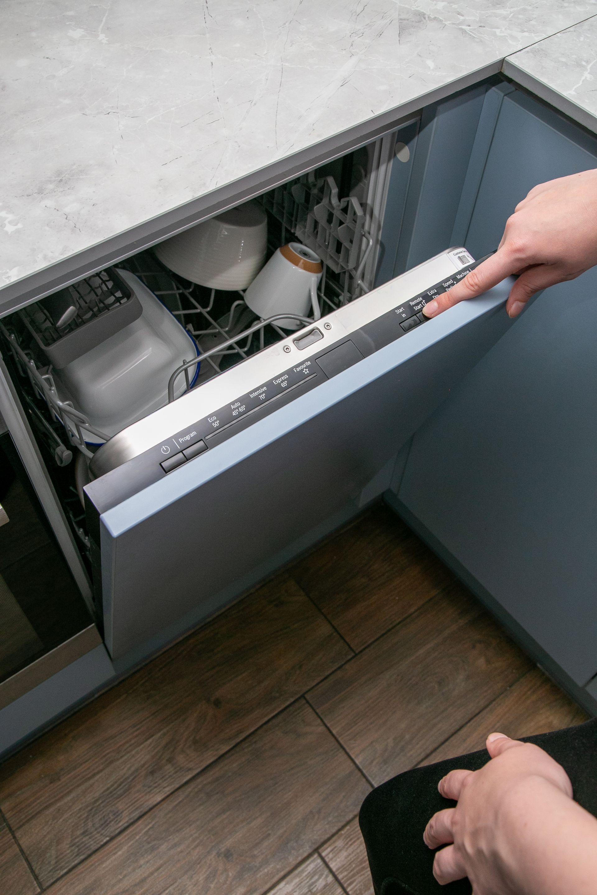 Open dishwasher being loaded in a kitchen, with dishes and utensils inside. Open dishwasher being loaded in a kitchen, with dishes and utensils inside.