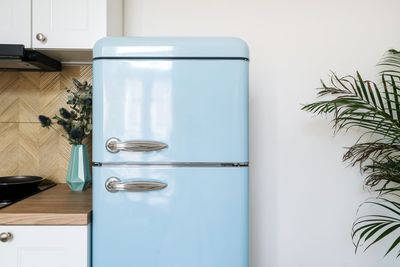 Technician applying a colored vinyl wrap film to a kitchen refrigerator.