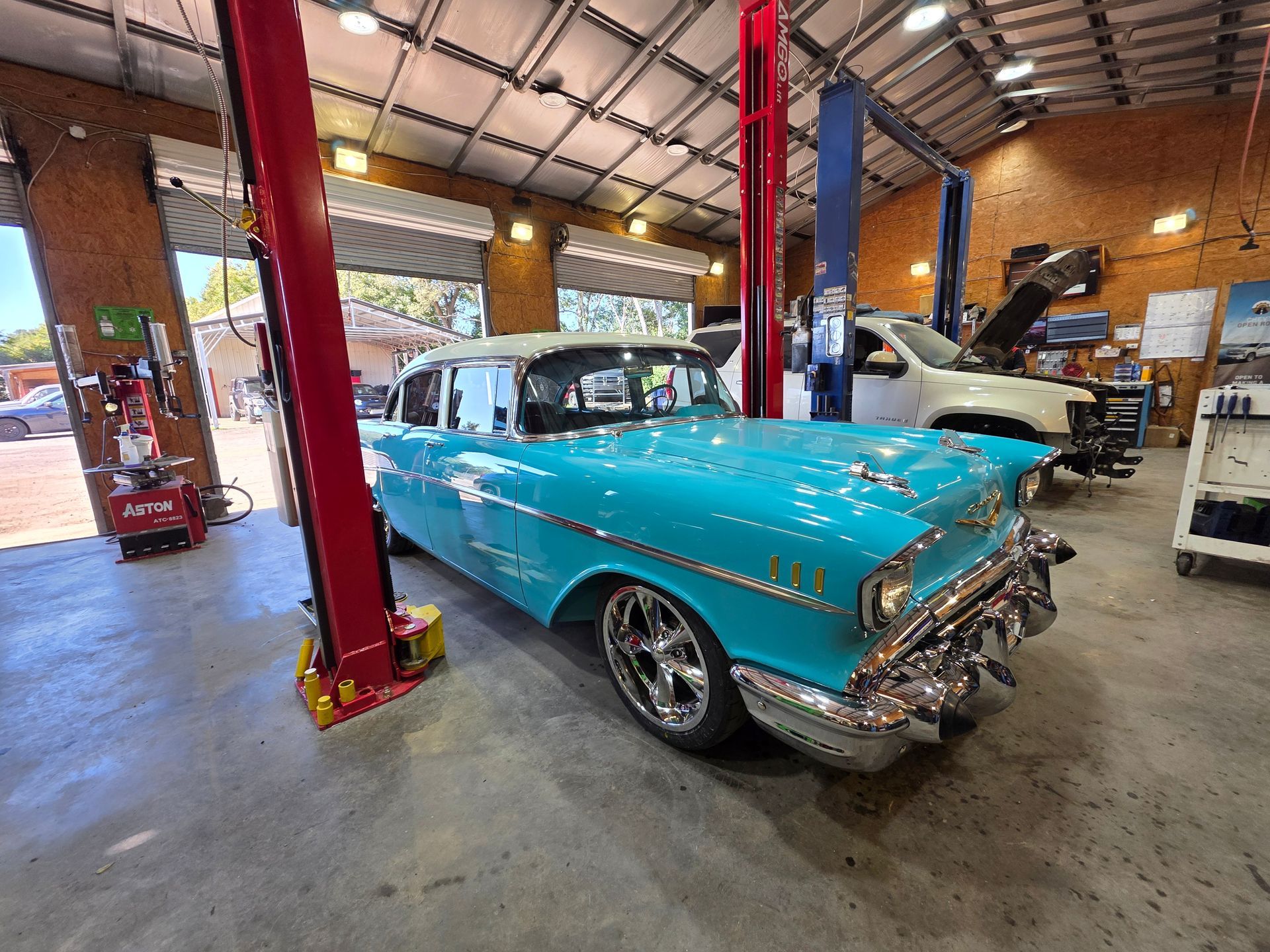 Turquoise classic car in an auto repair shop with lifts and tools around it | Masters Auto Group