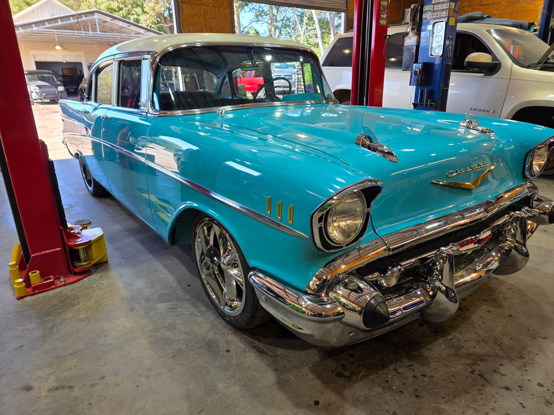 Turquoise 1950s classic car in an auto shop with red lifts and another car in the background | Masters Auto Group
