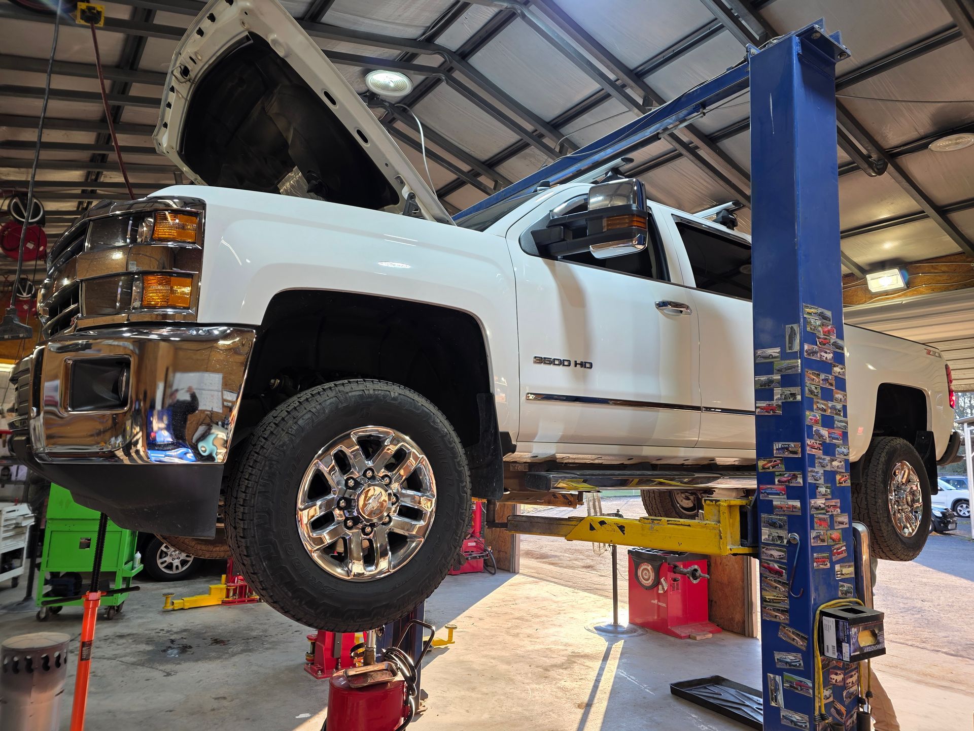 White lifted pickup truck on a blue vehicle lift inside an auto repair shop | Masters Auto Group