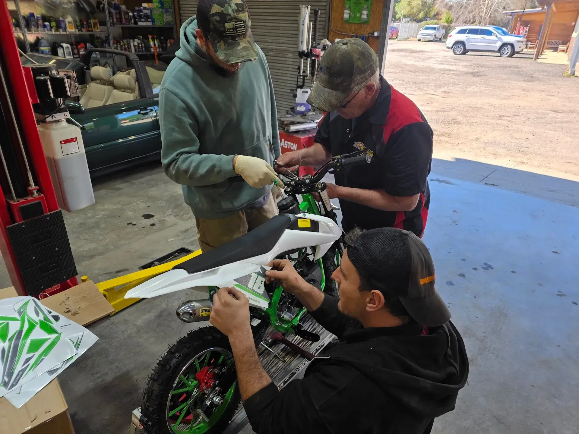 Mechanics Working on a White Dirt Bike in a Garage | Masters Auto Group