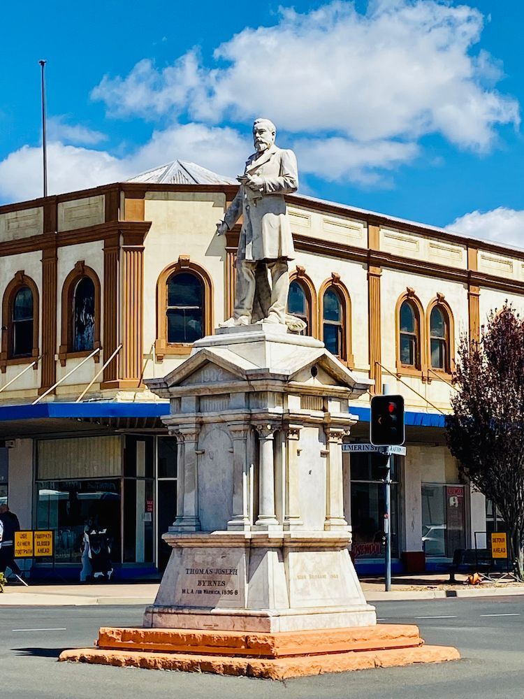 Statue of a Man in Front of a Two-story Building in a Town Square. Blue Sky With Clouds — Frontier Security in Warwick, QLD