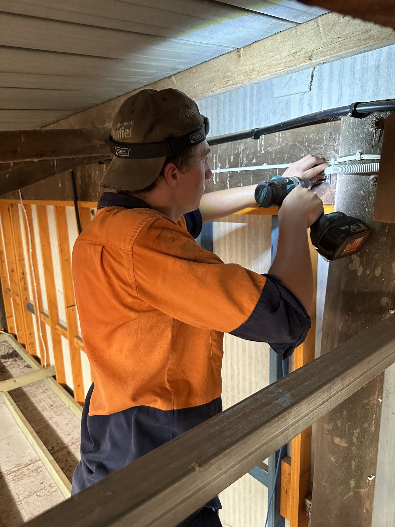 Man in Work Clothes Uses a Power Drill on a Structure, Illuminated by a Headlamp — Frontier Security in Gatton, QLD