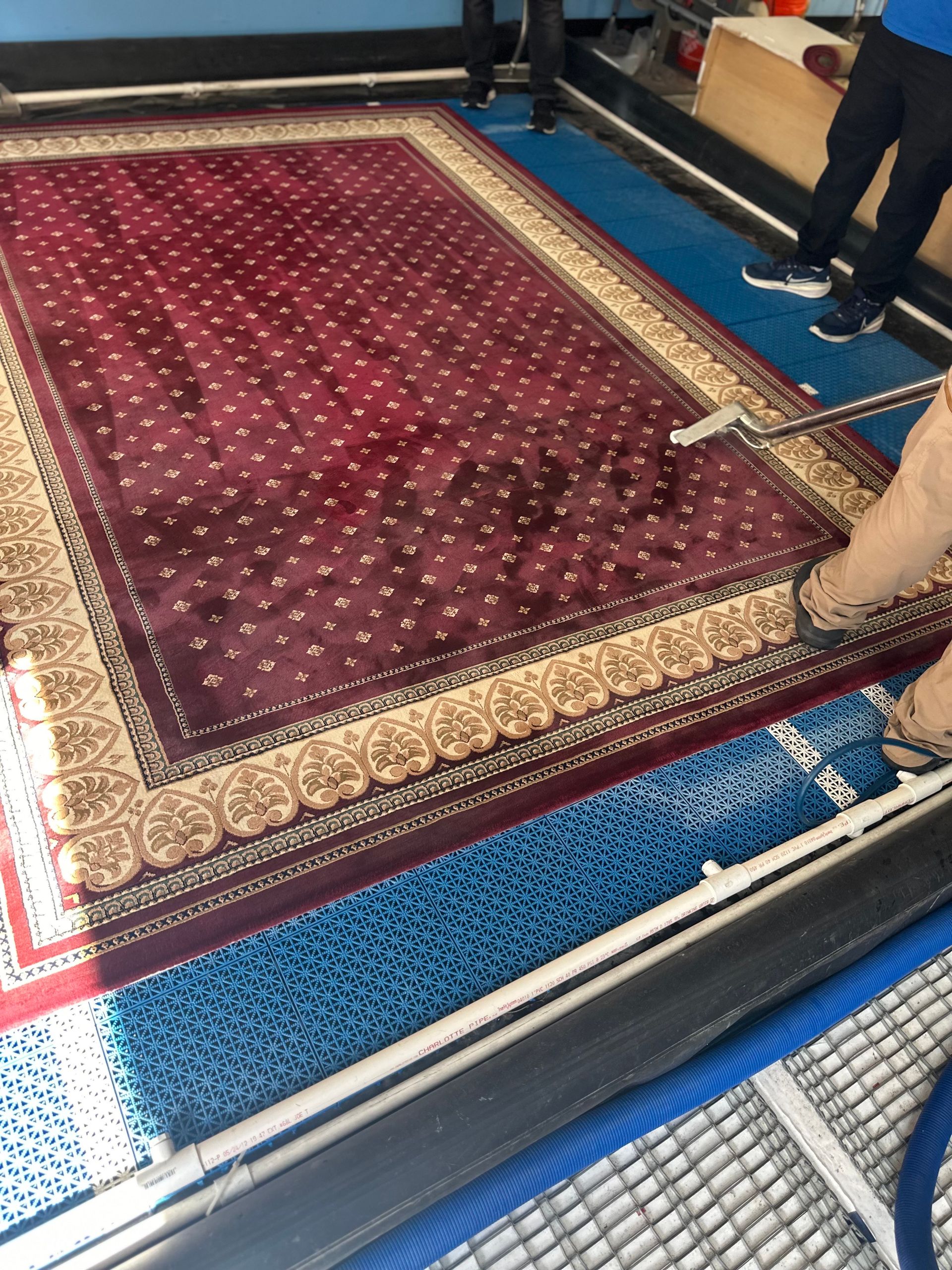 A man is cleaning a rug with a vacuum cleaner.