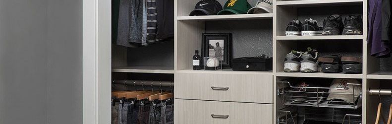 organized custom reach-in closet system filled of shoes, caps and pants
